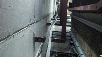 TÜV AUSTRIA entdeckt Mängel bei Aufzügen: TÜV AUSTRIA entdeckt Mängel bei Aufzügen: Schienenstrang des Gegengewichts von oben nach unten blickend im Aufzugsschacht